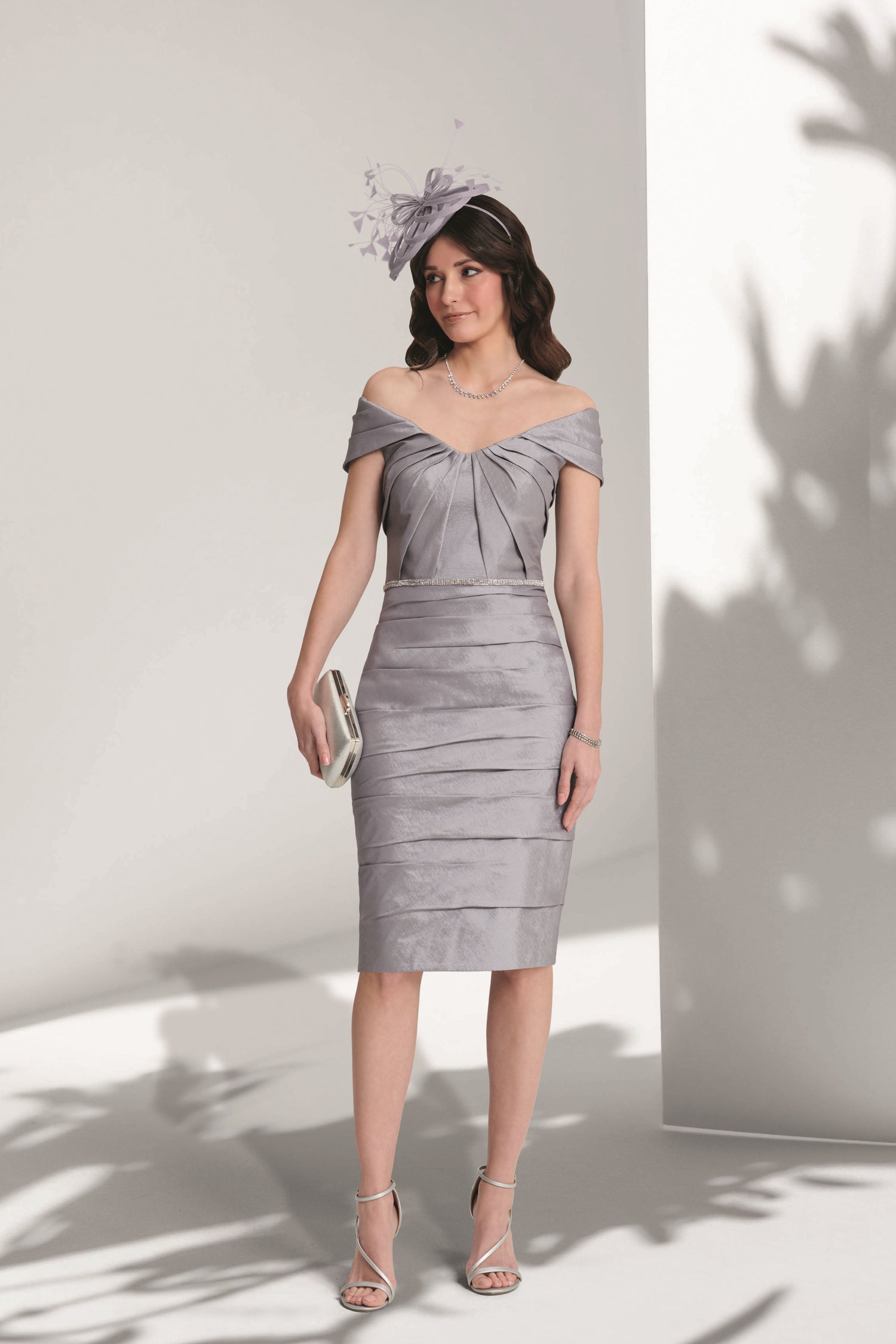 Woman wearing a silver off-shoulder dress against a white background