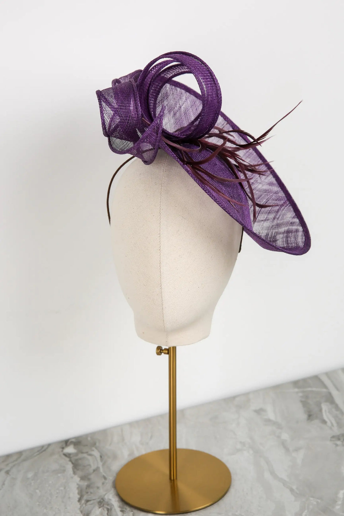 Purple decorative hat on a mannequin head against a white background