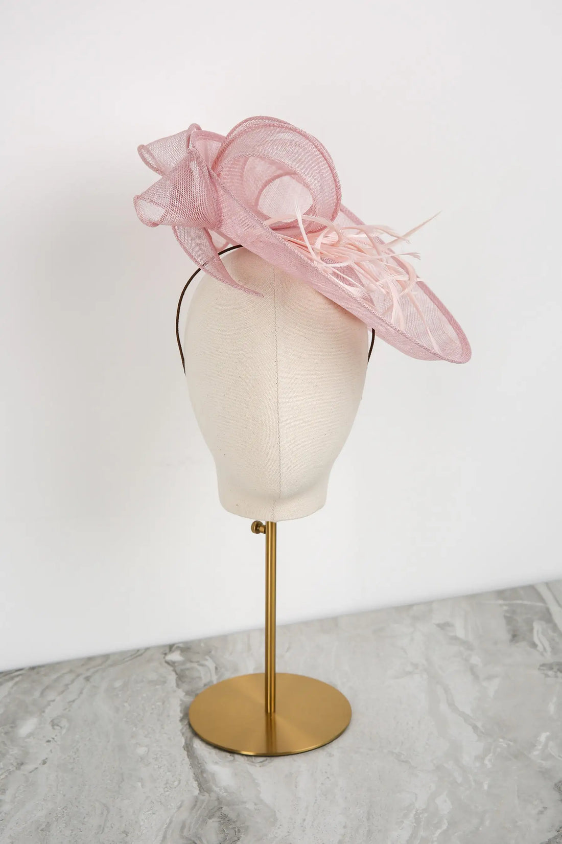 Pink decorative hat on a mannequin head with a white background