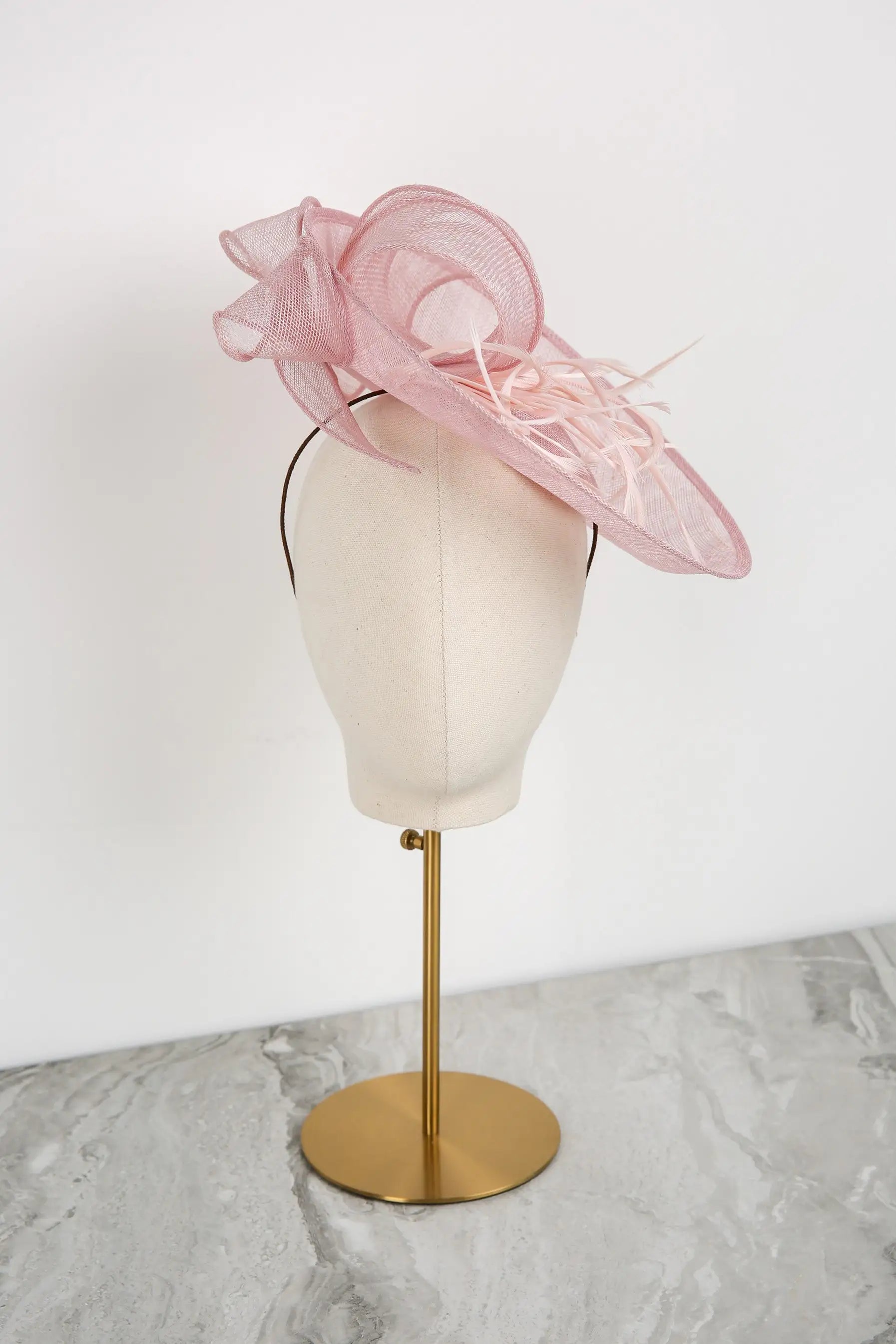 Pink decorative hat on a mannequin head with a white background