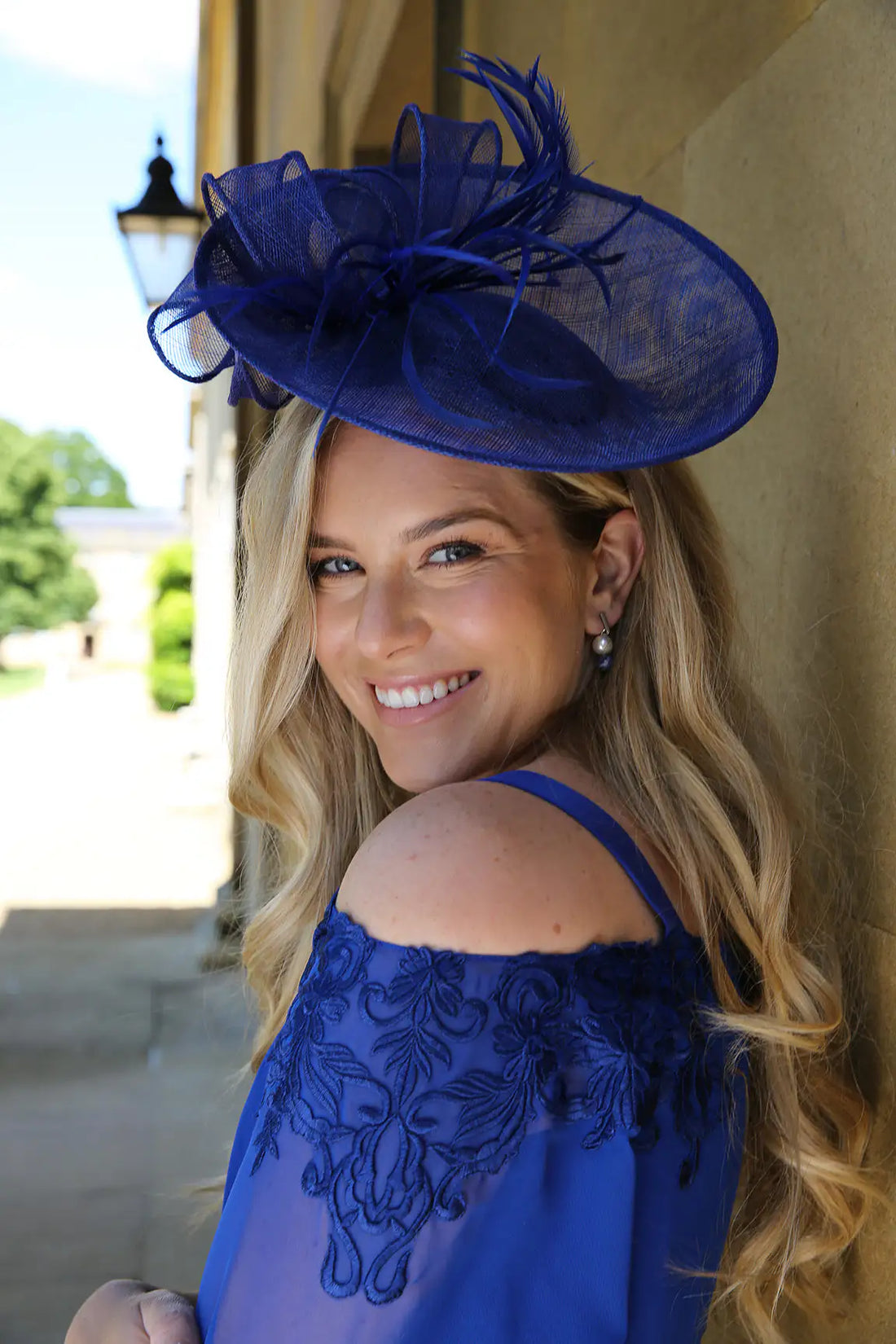 A woman wearing a blue fascinator with a sinamay base and delicate matching feathers.