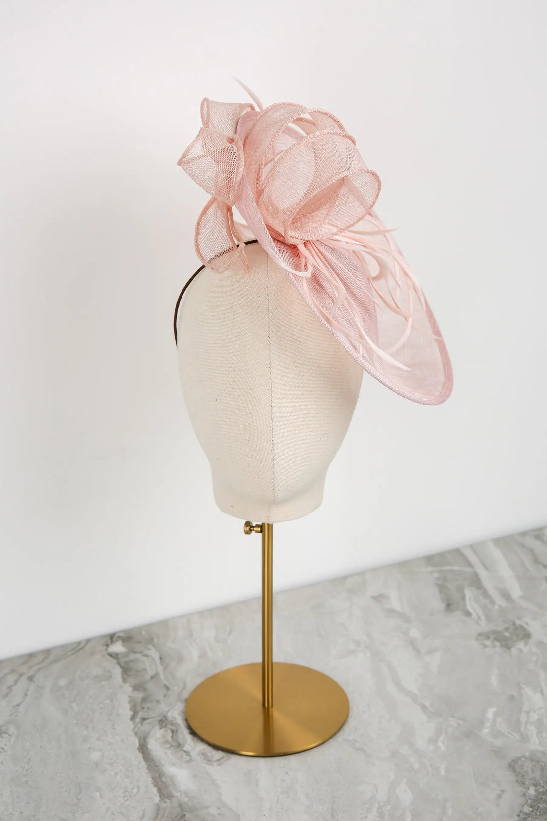 Pink fascinator on a mannequin head against a white background