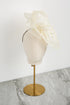 White fascinator on a mannequin head with a gold stand against a white background
