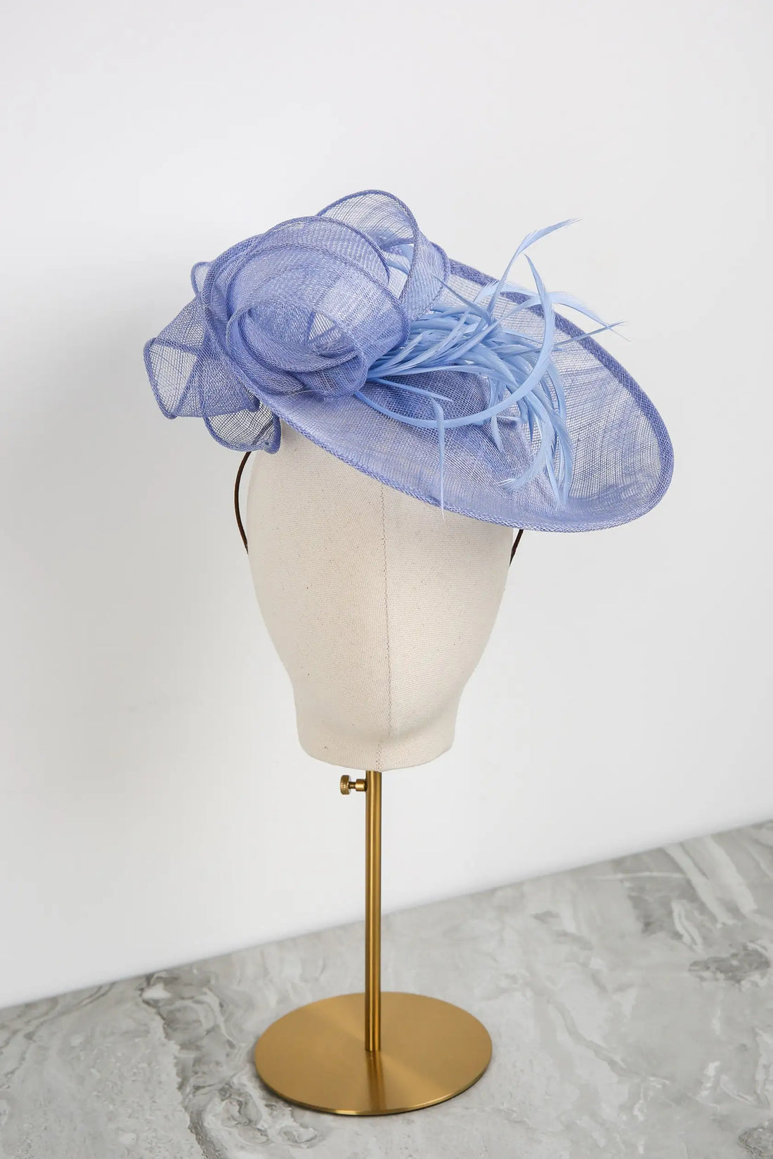 Blue decorative hat on a mannequin head against a white background