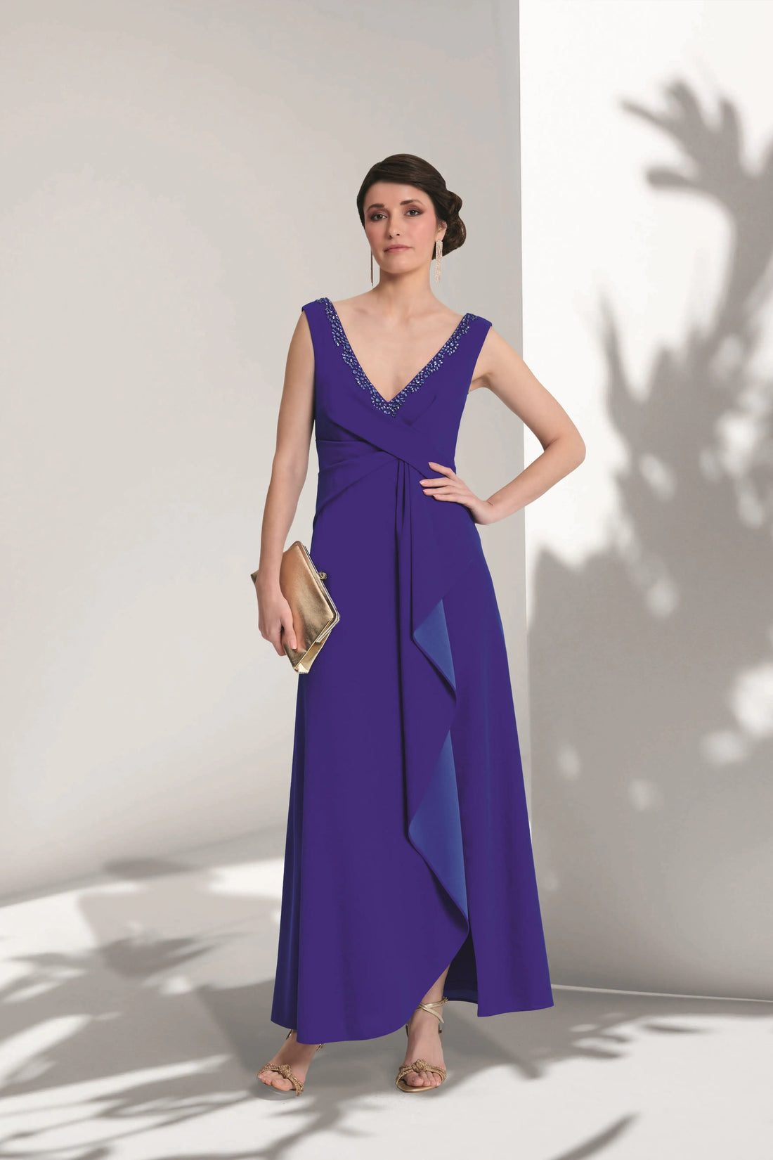 Woman wearing a purple evening gown against a white wall