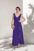 Woman wearing a purple evening gown against a white wall