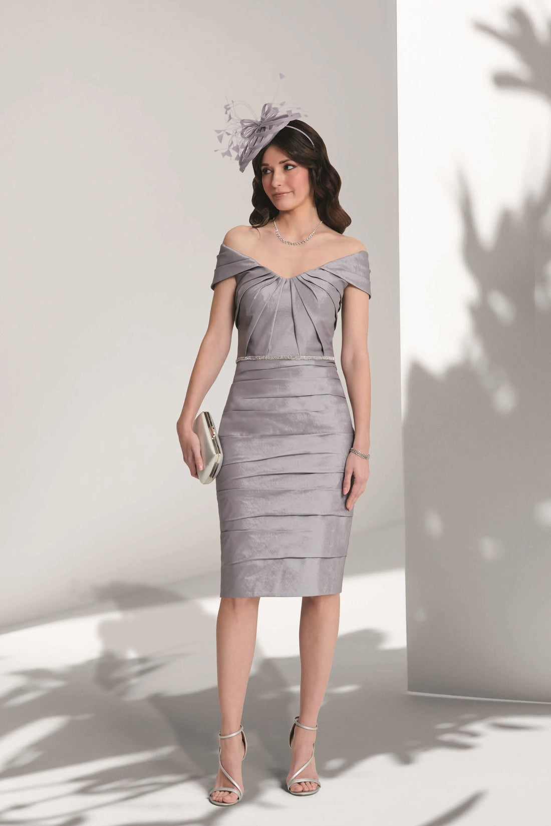 Woman wearing a silver off-shoulder dress against a white background