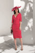 Woman wearing a red dress and hat against a white wall