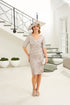 Woman in a light gray dress and hat standing in a modern interior setting