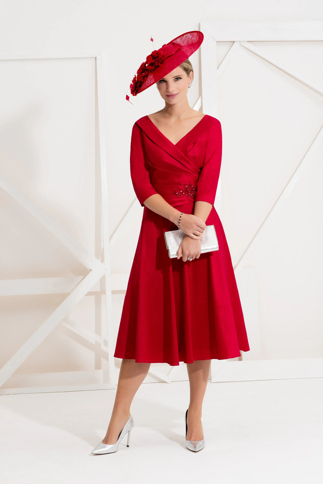 A woman in a red knee-length dress with beaded detail at the waist, featuring an &