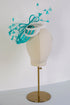 Teal and white decorative headpiece on a mannequin head against a white background