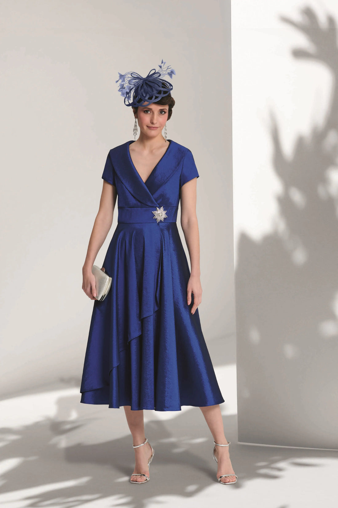Woman wearing a blue dress with a floral headpiece against a white wall