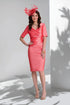 Woman wearing a pink dress and matching fascinator against a white background