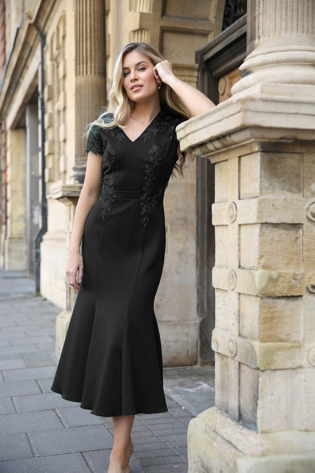 Woman in a black dress with embroidered detailing.