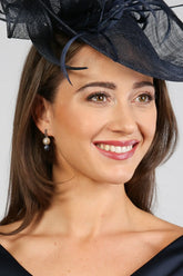 A woman wearing navy and white sodalite and pearl drop earrings with a smile on her face.