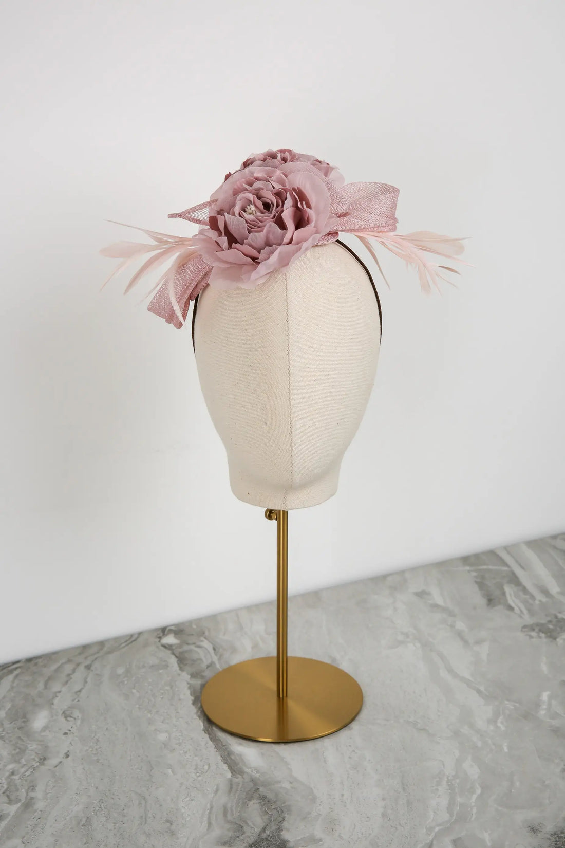Pink floral headpiece on a mannequin head against a white background