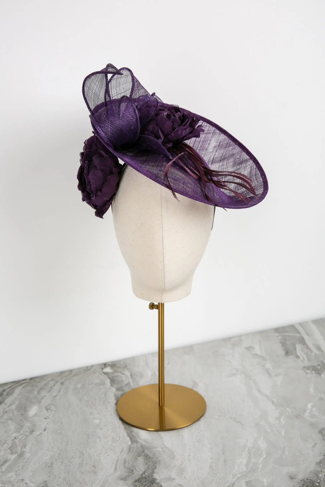 Purple decorative hat on a mannequin head against a white background