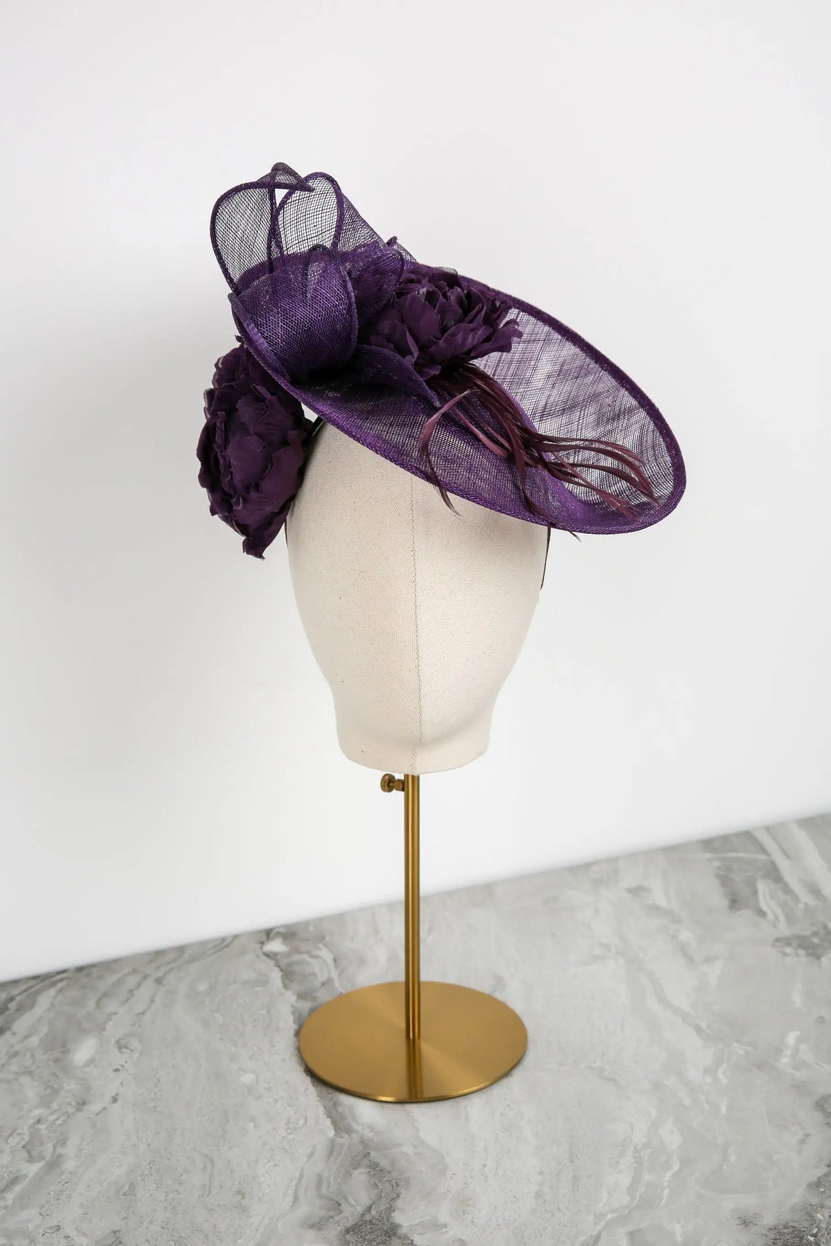 Purple decorative hat on a mannequin head against a white background