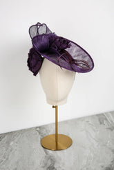 Purple decorative hat on a mannequin head against a white background