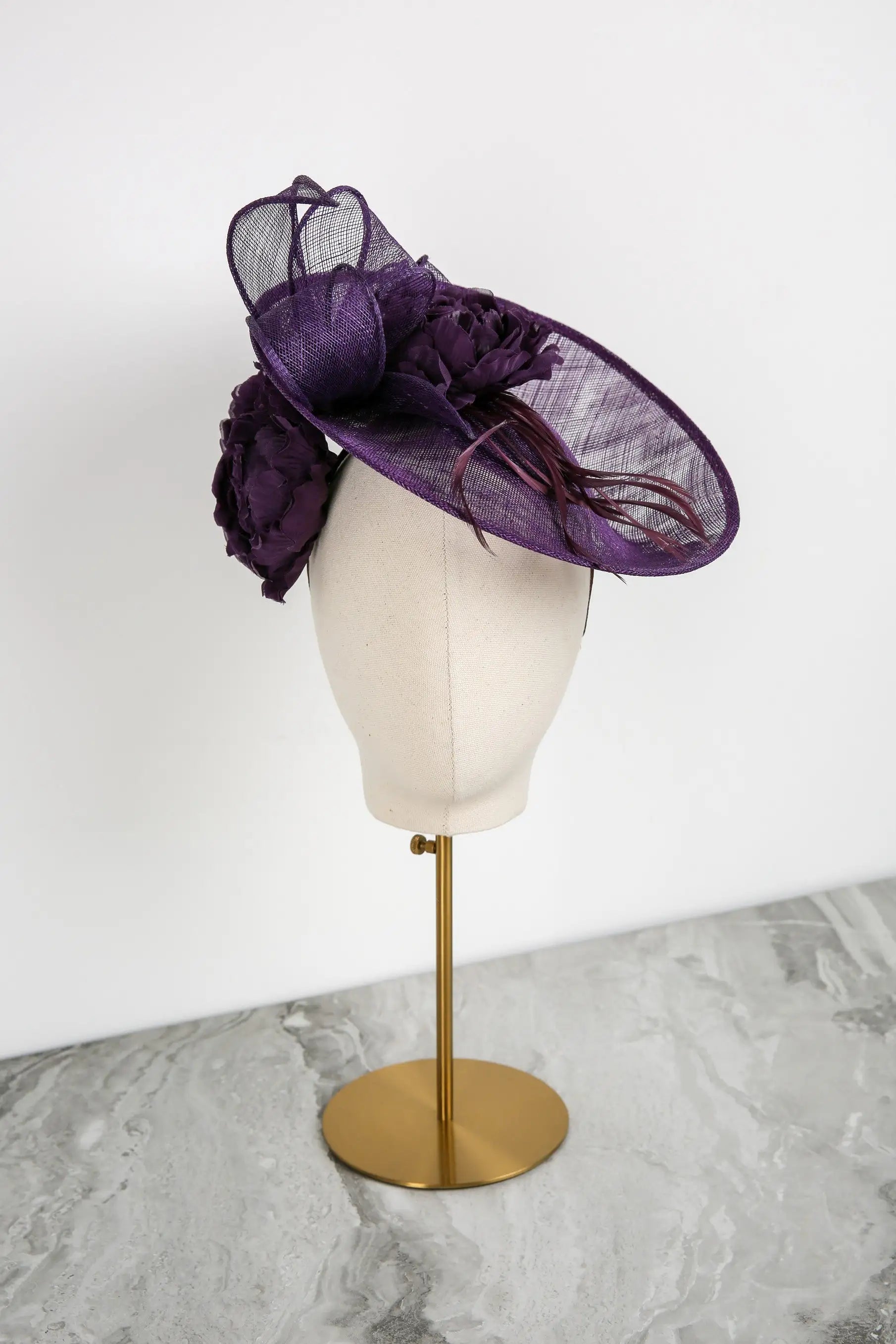 Purple decorative hat on a mannequin head against a white background