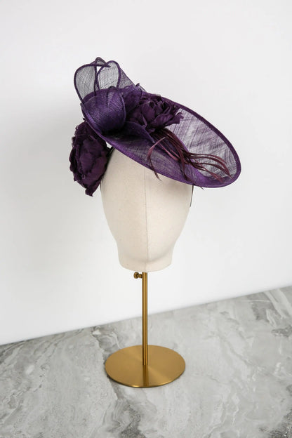 Purple decorative hat on a mannequin head against a white background