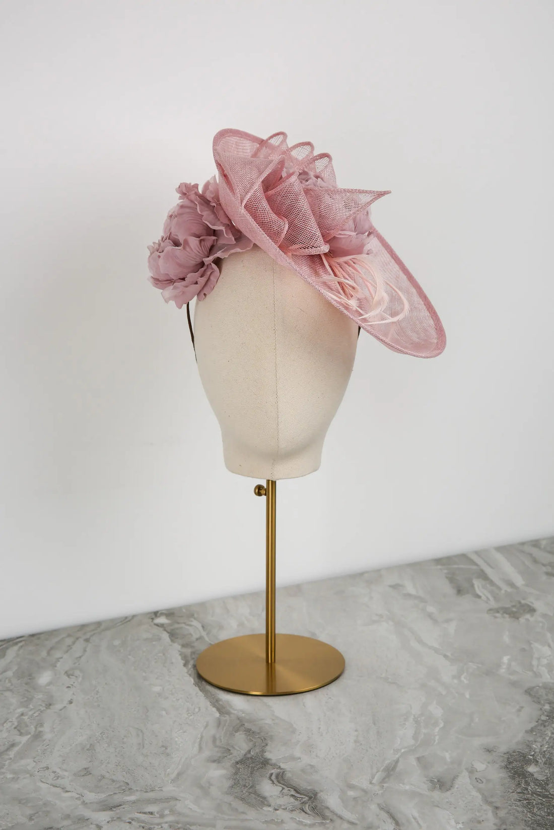 Pink floral headpiece on a mannequin head against a white background