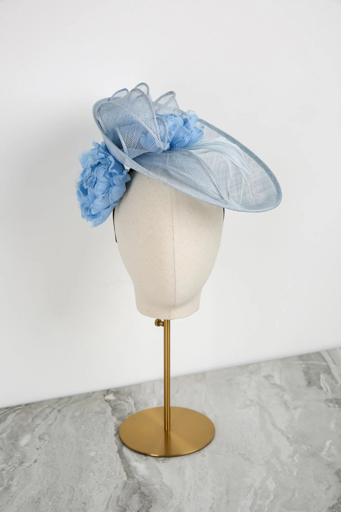 Light blue decorative hat on a mannequin head against a white background