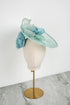 Light blue and green decorative hat on a mannequin head against a white background