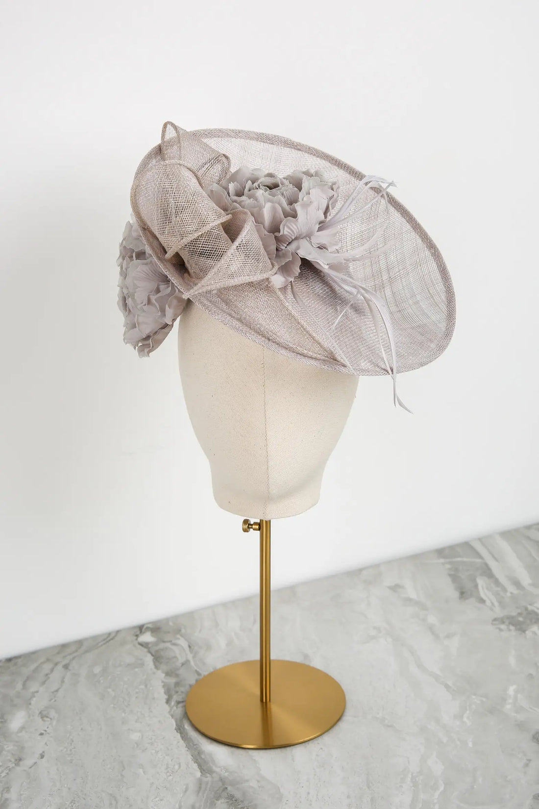 Silver decorative hat on a mannequin head against a white background