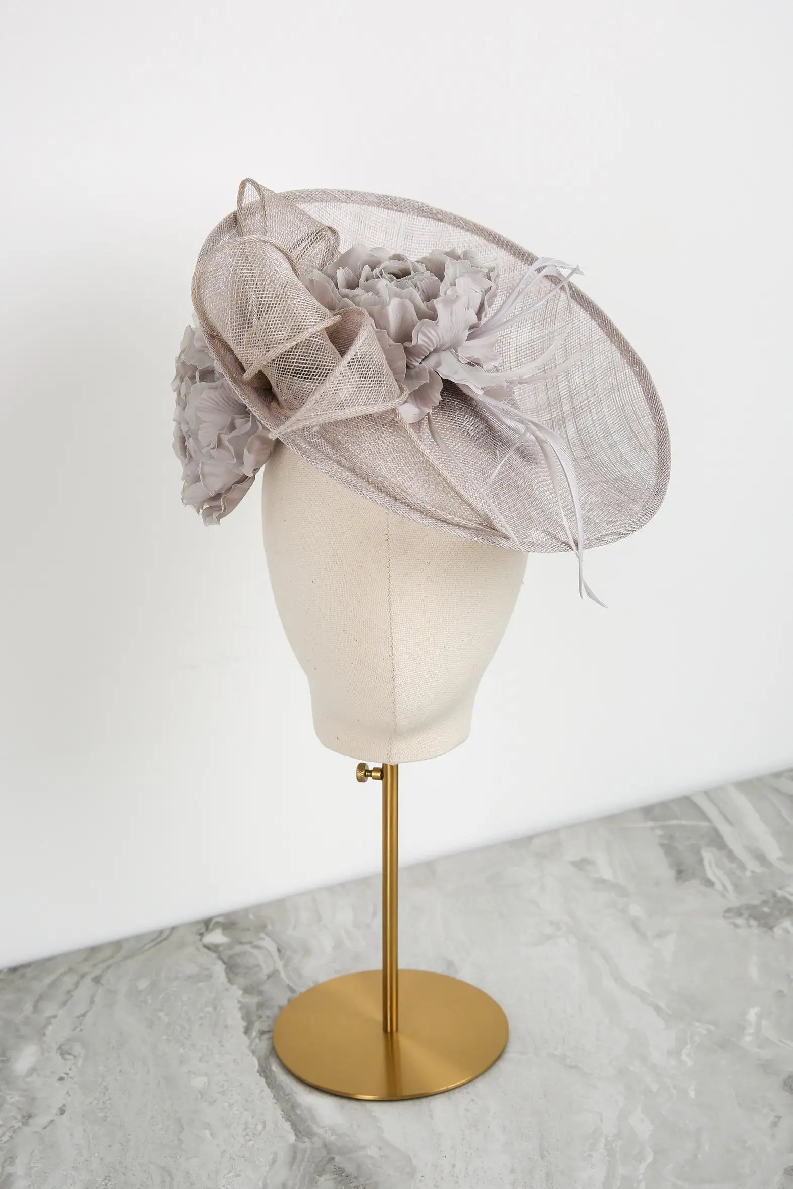 Silver decorative hat on a mannequin head against a white background