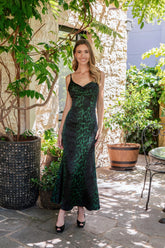 Woman in a green dress standing outdoors among plants