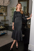 Woman in a black dress standing in an elegant room with decorative elements.