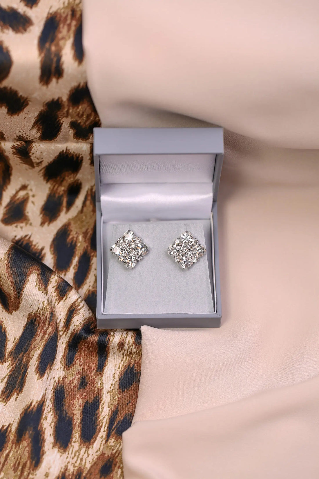Silver earrings in a box on a leopard print fabric background