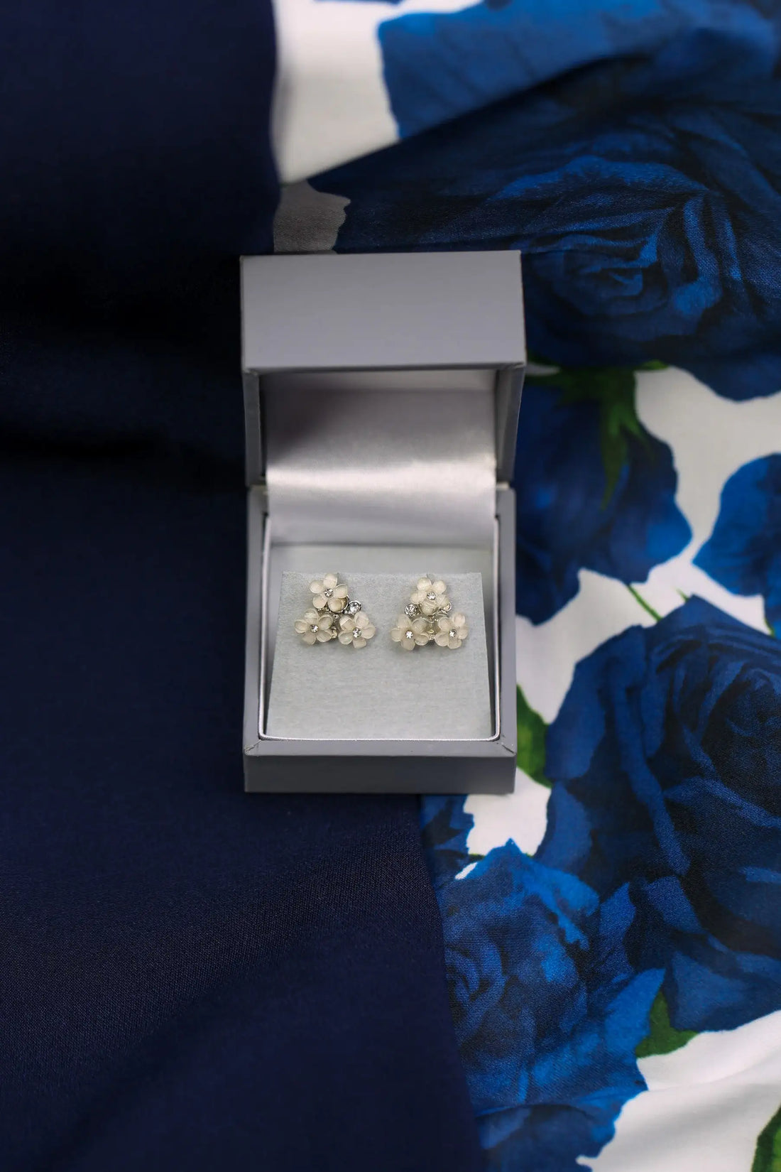 Pair of floral earrings in a grey box on a floral fabric background