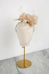 Beige fascinator on a mannequin head with a gold stand against a white background