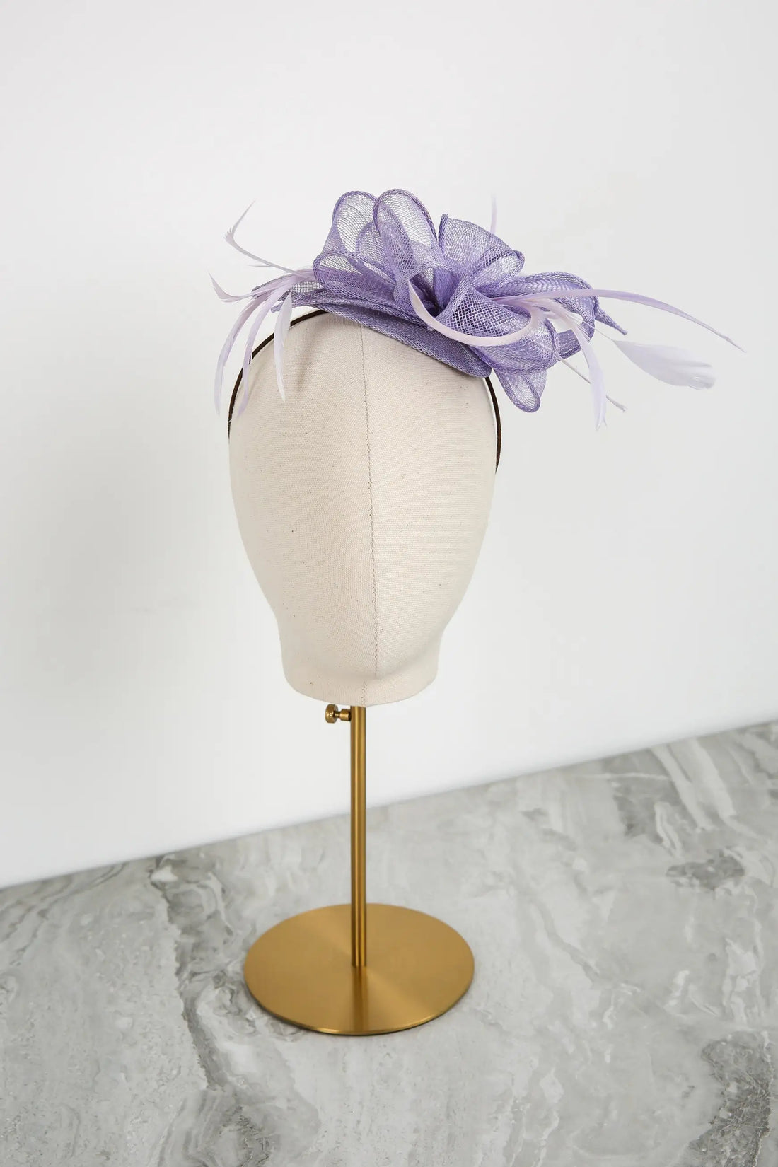Lavender fascinator on a mannequin head against a white background