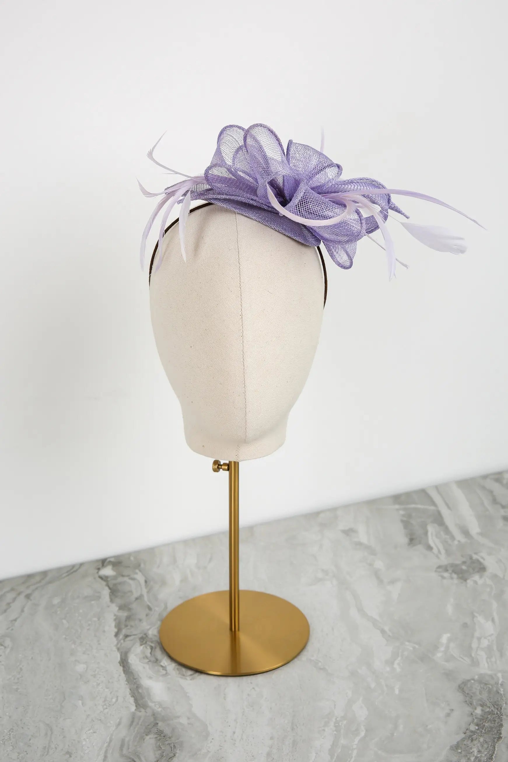 Lavender fascinator on a mannequin head against a white background