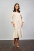 A woman models the Whitney Sleeved Midi Dress in almond colour, featuring long sleeves and a flared skirt, against a neutral background.